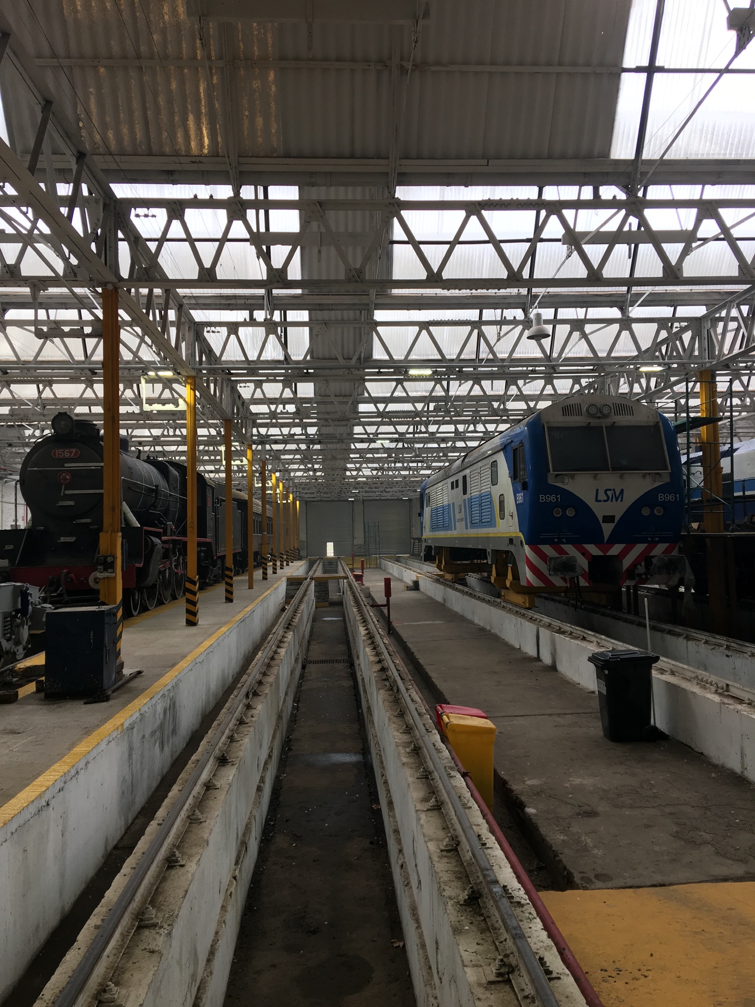 Interior del Taller Ferroviario Mechita con locomotoras y bandejas de iluminación.